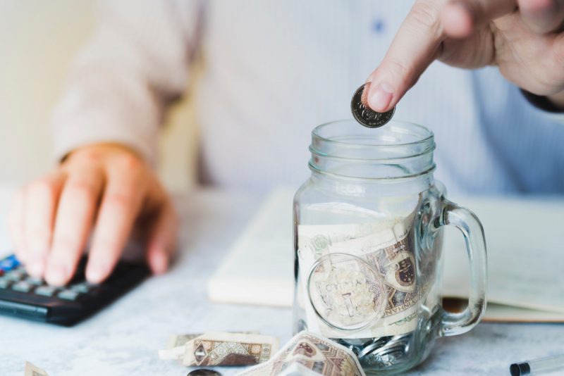 hand putting coin inside jar 23 2148081097